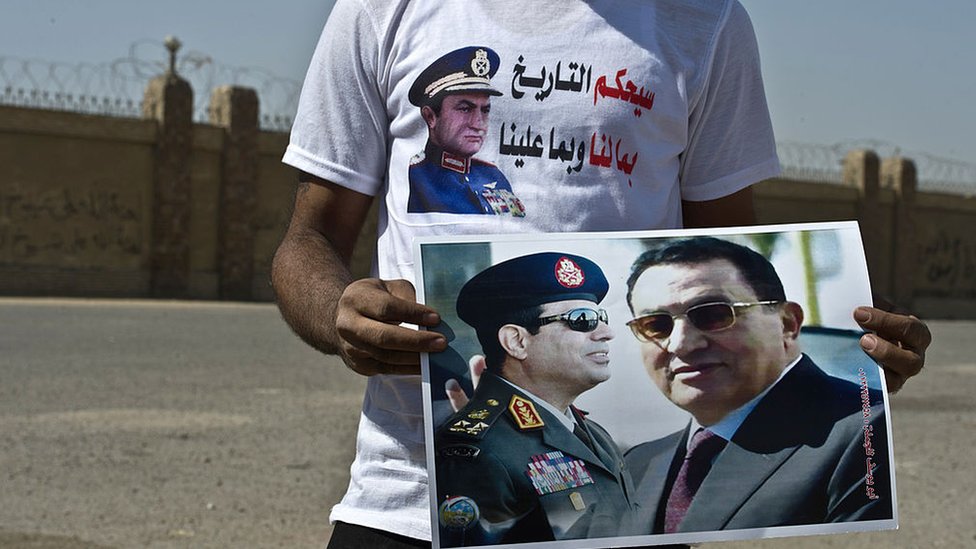 رجل يحمل لافتة تجمع بين مبارك والسيسي (أرشيفية)