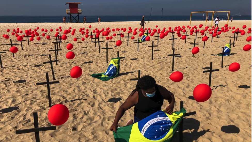 متظاهر من منظمة "ريو دي باز" غير الحكومية يربط العلم البرازيلي بصليب في شاطئ كوباكابانا في 8 أغسطس 2020 في ريو دي جانيرو بالبرازيل