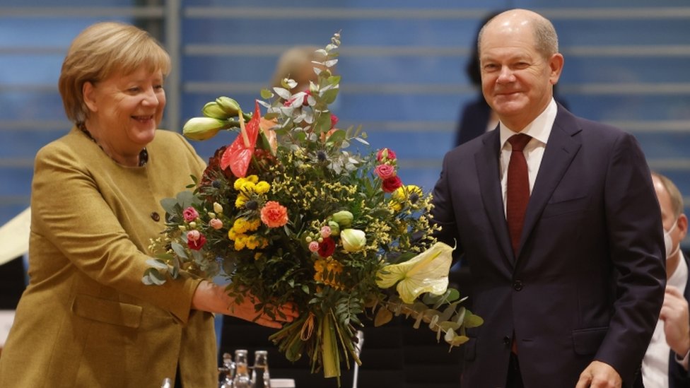 المستشارة بالإنابة أنجيلا ميركل (إلى اليسار) تتسلم باقة من الزهور من وزير المالية بالإنابة ونائب المستشار أولاف شولتز أثناء وصولها لحضور الاجتماع الأسبوعي لمجلس الوزراء في برلين ، ألمانيا ، 24 نوفمبر 2021