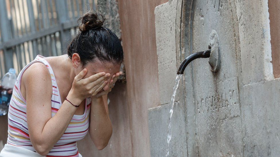 امرأة أوروبية تغسل وجهها للتخفيف من درجة الجرارة العالية خلال الصيف.