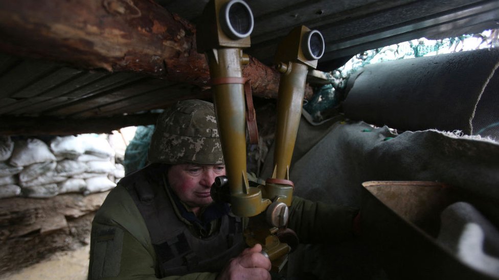 جندي أوكراني يراقب من خلال منظار على خط المواجهة مع الانفصاليين المدعومين من روسيا بالقرب من قرية لوغانسك 2022