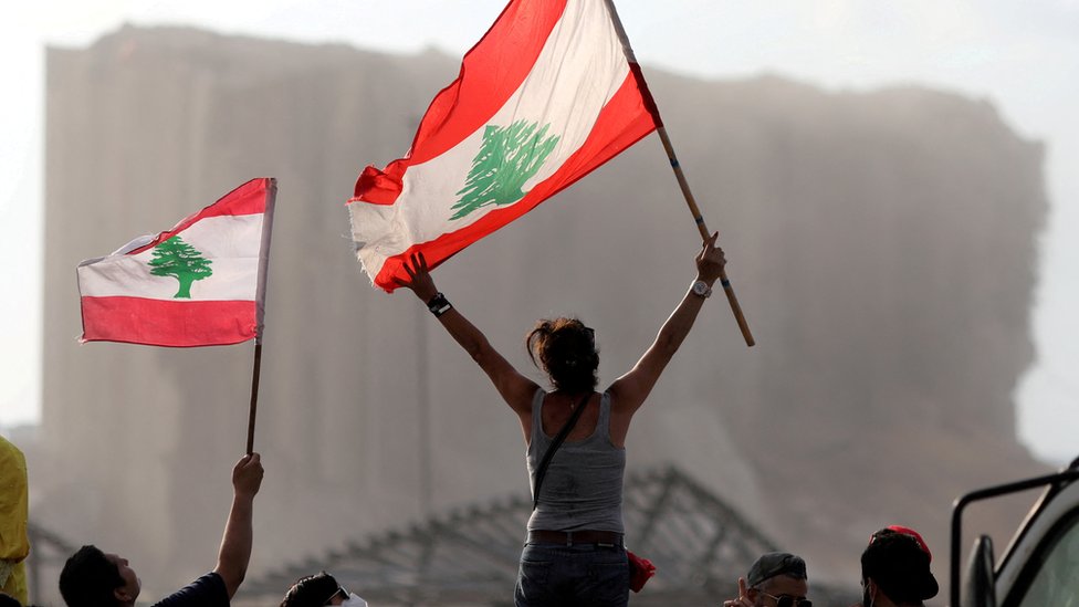 متظاهرون يلوحون بالأعلام اللبنانية خلال احتجاجات بالقرب من موقع انفجار مرفأ بيروت، لبنان، 11 أغسطس/آب 2020.