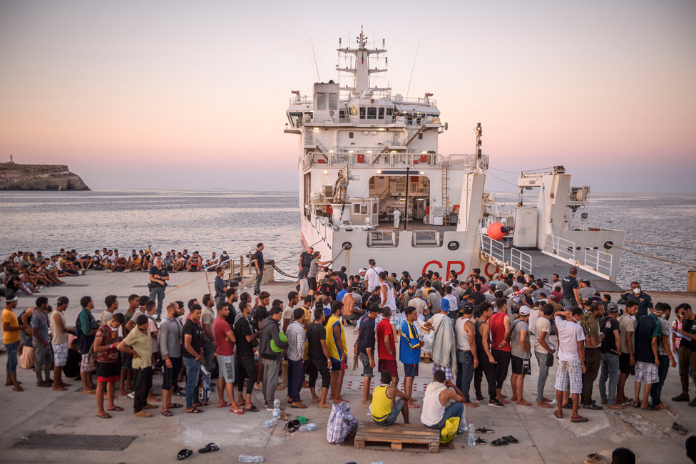 مهاجرون ينتظرون على متن سفينة خفر السواحل في جزيرة لامبيدوزا قبل نقلهم إلى بورتو إمبيدوكلي في صقلية بإيطاليا.