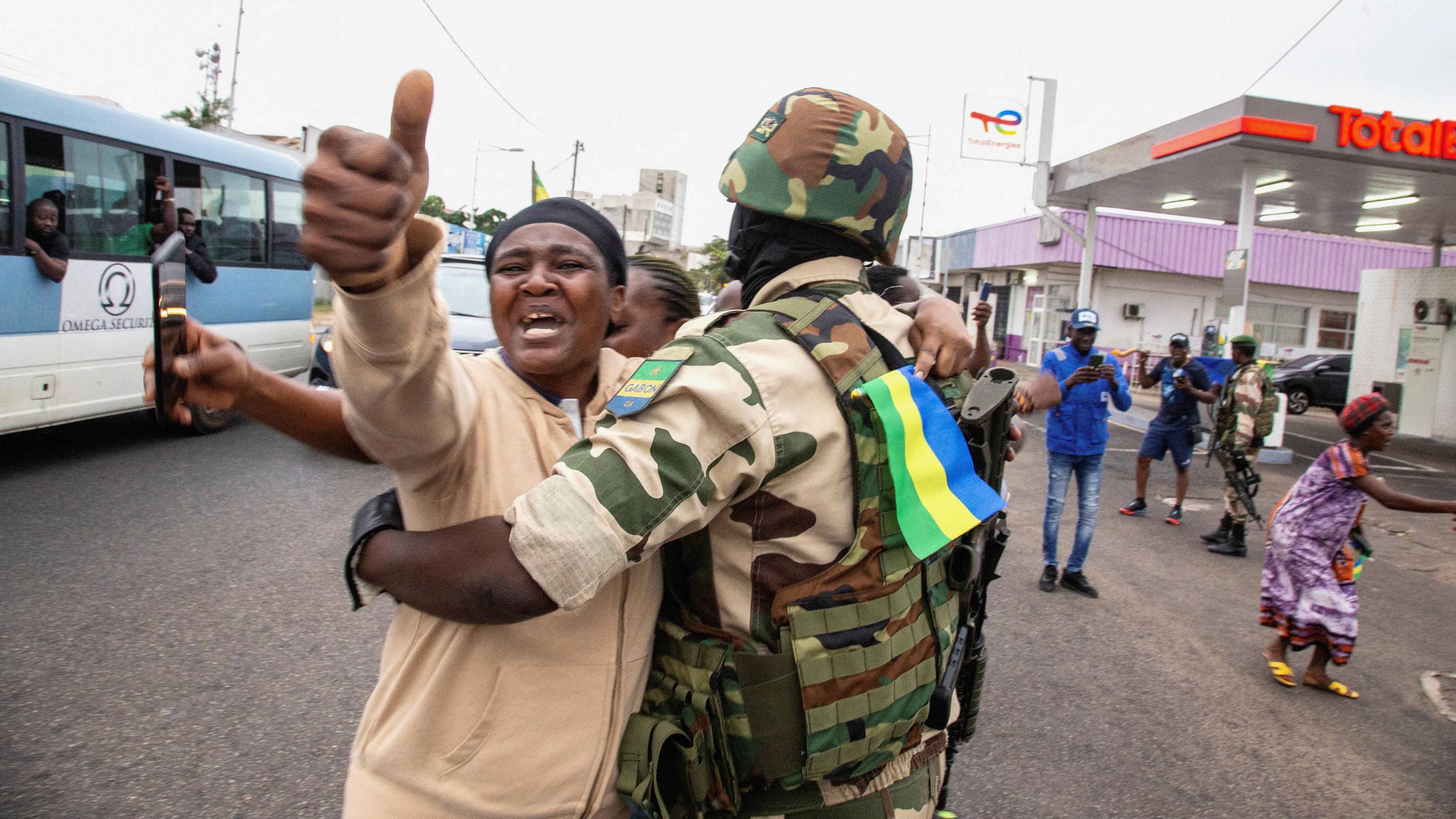 امرأة تحتضن جنديًا وهي تحتفل دعما للانقلابيين في أحد شوارع بورت جنتيل بالغابون