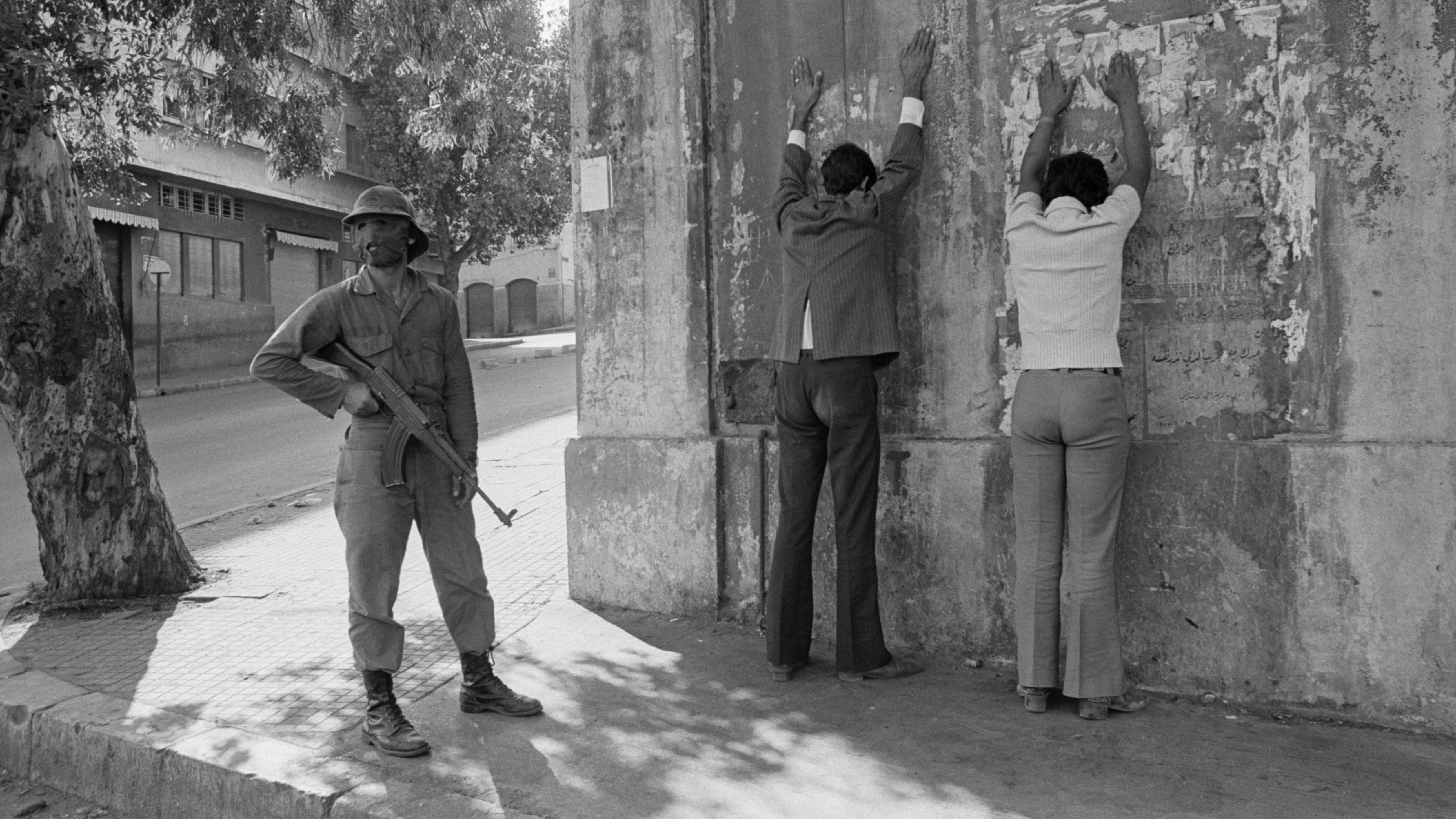 أحد رجال الميليشيا في بيروت يراقب شخصين خلال الحرب الأهلية 