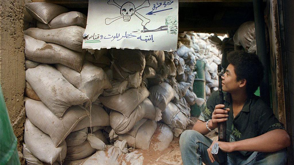 طفل مسلح يجلس خلف متراس في مخيم شاتيلا في بيروت